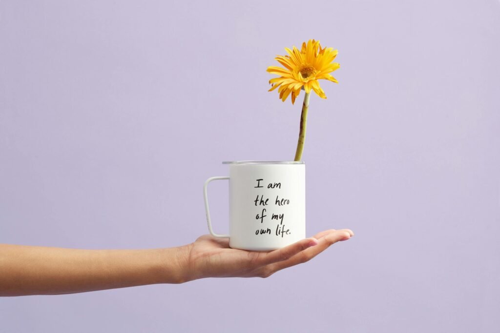 pexels photo 2228585 2228585 Hand holding a mug with a sunflower and motivational quote, set against a purple background.