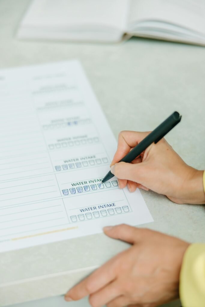 pexels photo 8844562 8844562 Hands filling out a nutrition plan with a focus on water intake. Ideal for health and wellness themes.